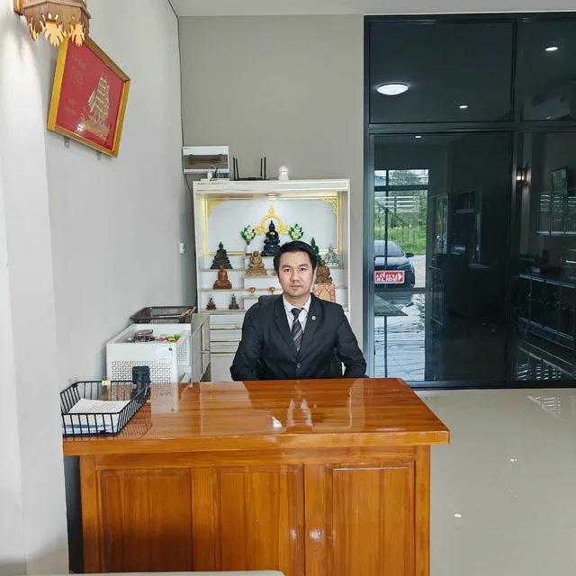 ทนายคมสัน แช่มช้อย ในชุดสูท นั่งที่โต๊ะรับปรึกษาคดีในสำนักงาน